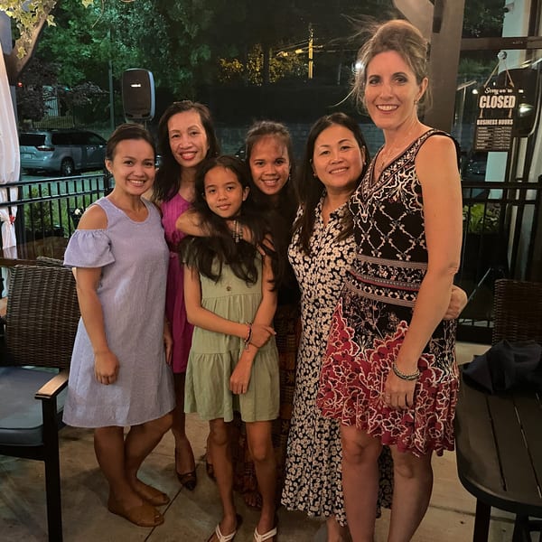 Six women and girls smiling together on an outdoor patio at Colonial Kitchen and Bar.