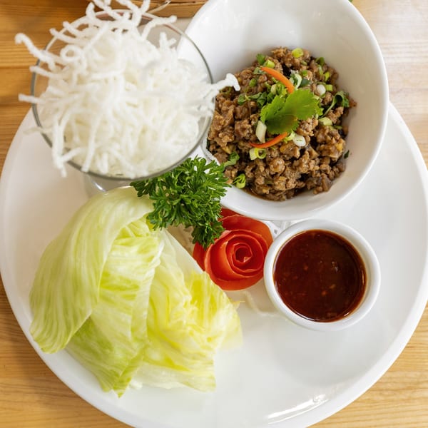 Thai lettuce wraps with minced meat, crispy noodles, fresh lettuce, and dipping sauce.