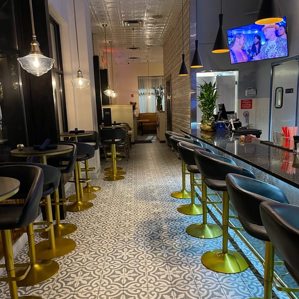 Interior view of Colonial Kitchen and Bar, showing a long bar with stools and small tables.